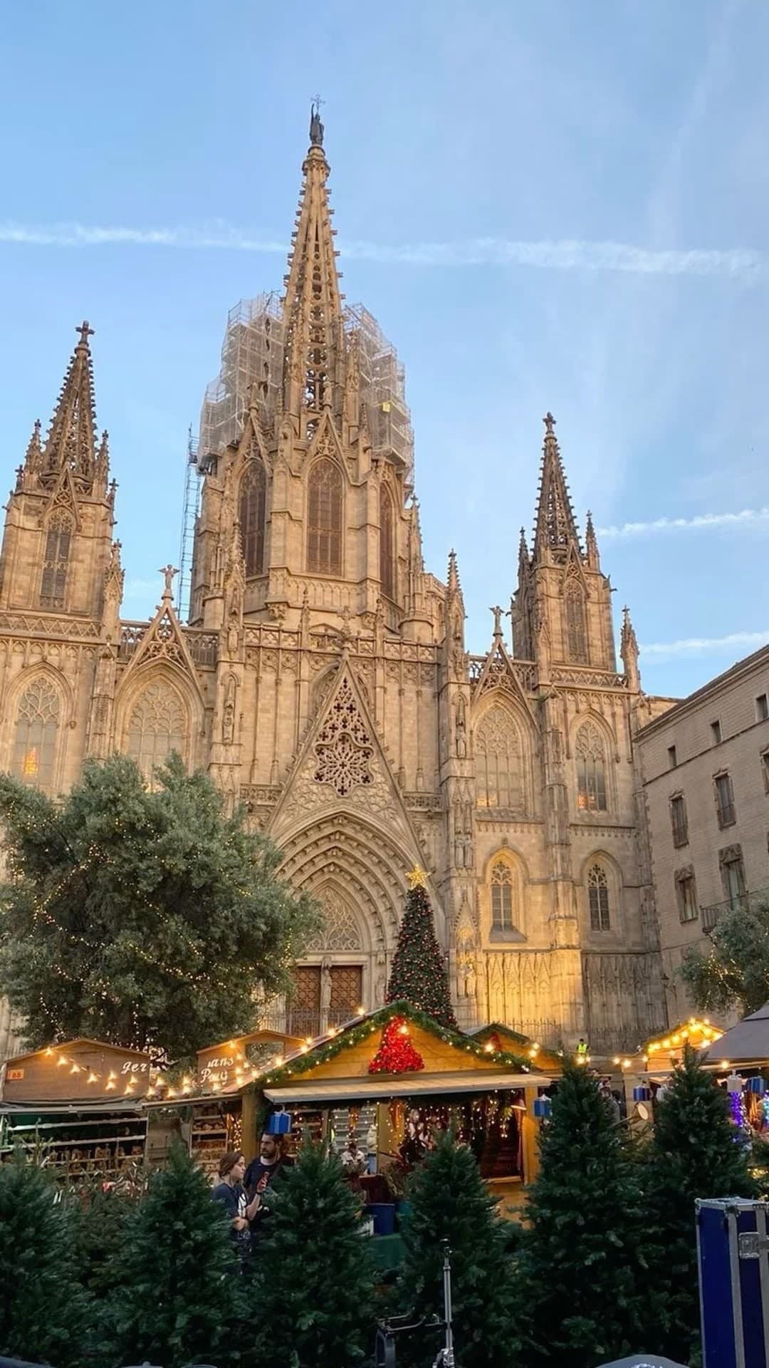 The Gothic cathedral of Barcelona at golden hour, with Christmas market stalls in front