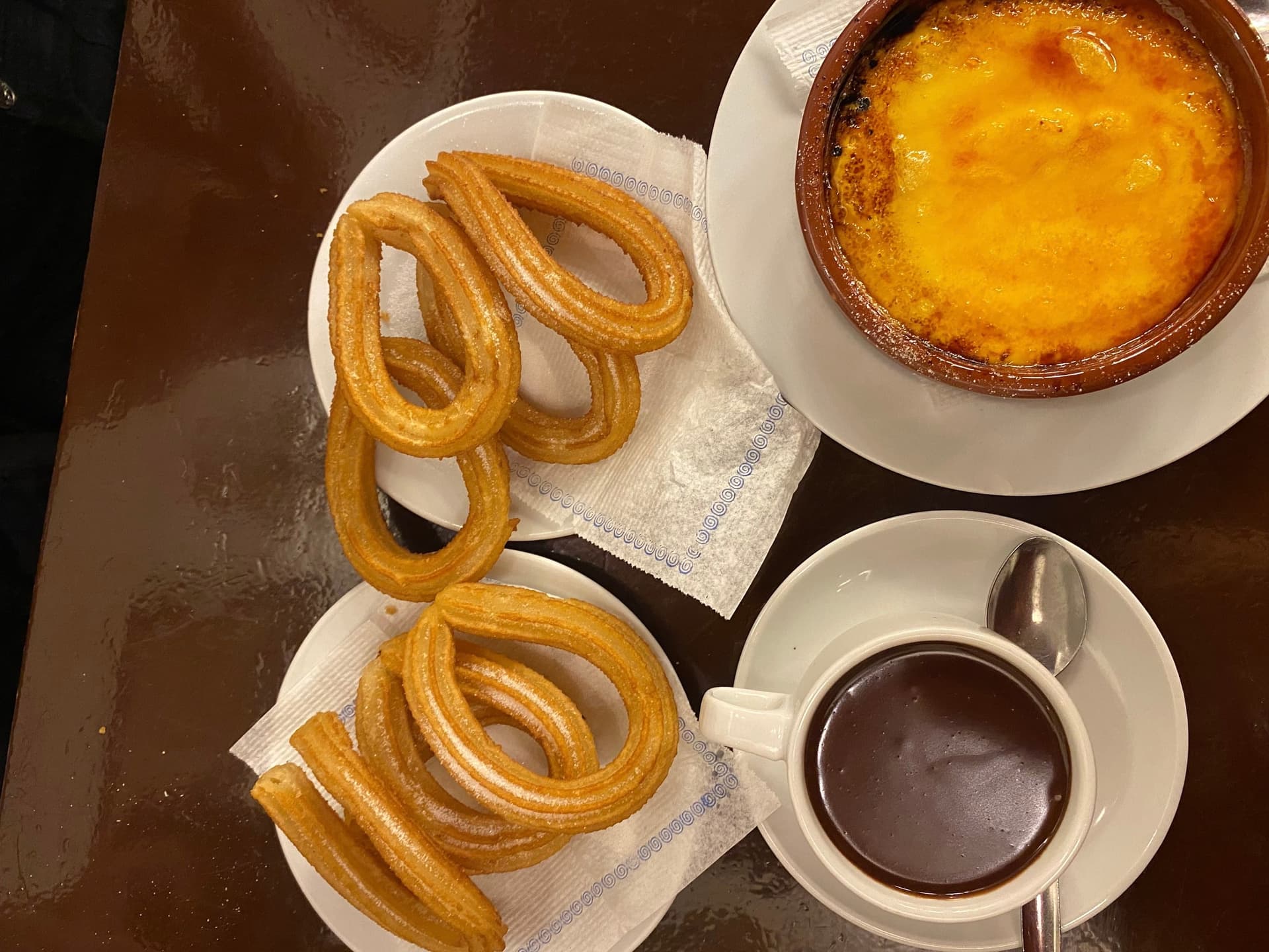 Churros, hot chocolate and crema catalana on a table, from above