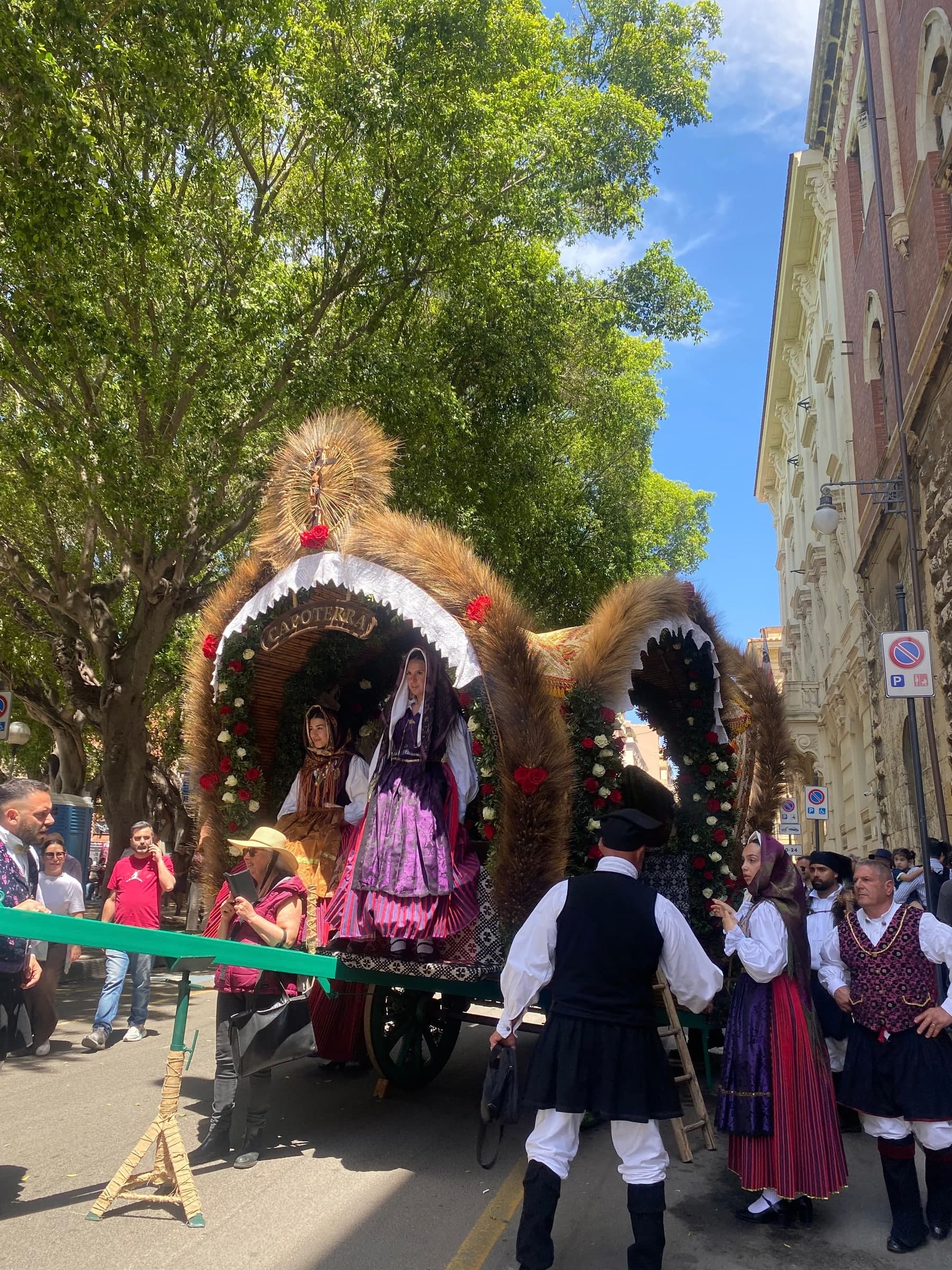 Decorated wooden carts and people in Sardinian traditional costume in a city street