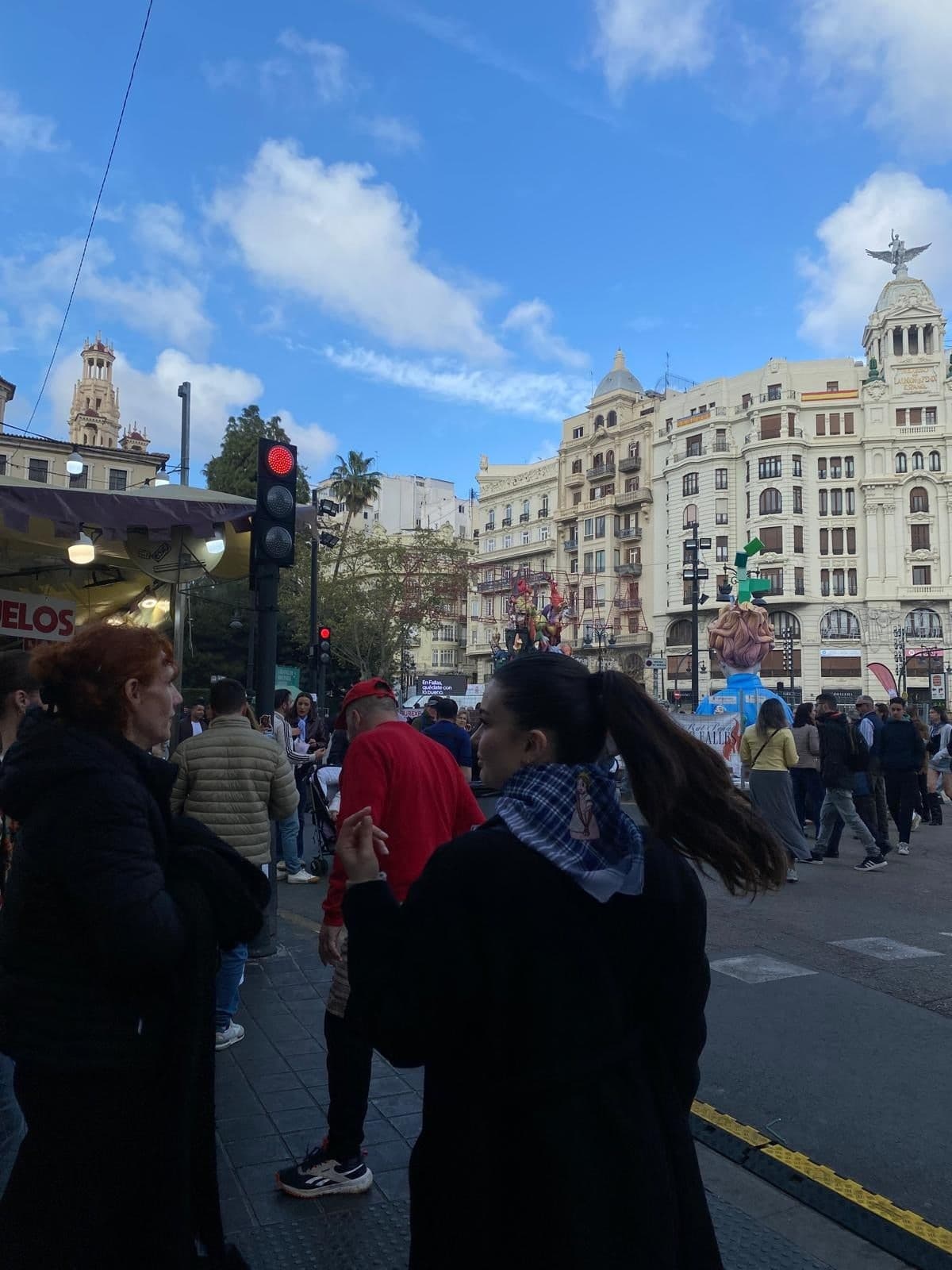 Eleonora in a busy city square, turning to look back over her shoulder